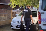A forensic policeman outside a house carrying a case