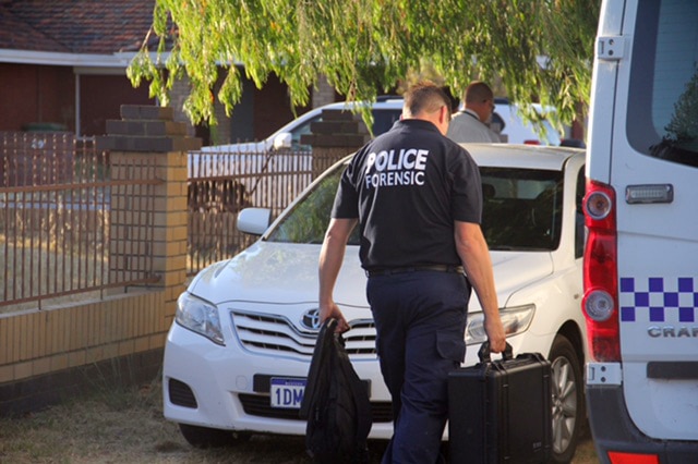 A forensic policeman outside a house carrying a case
