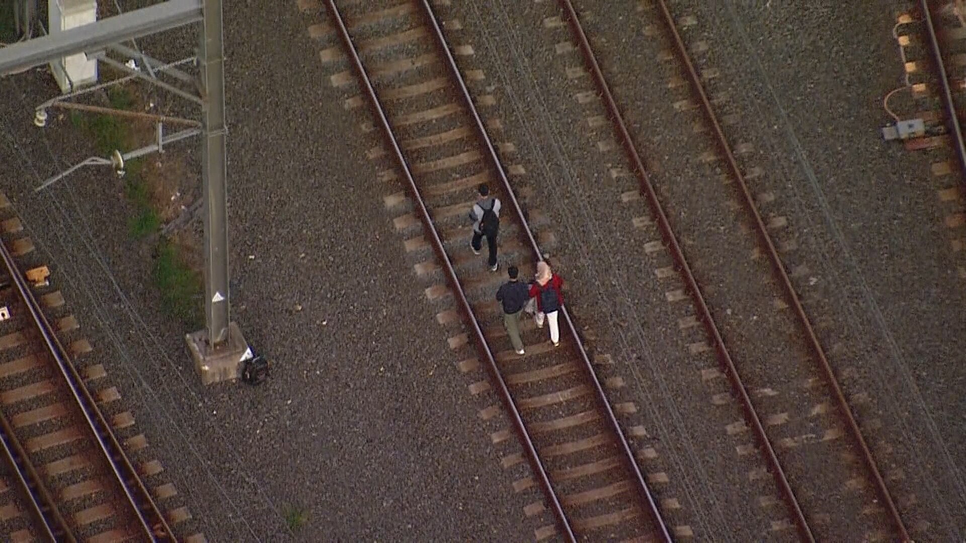 Los pasajeros caminan por vías de tren después de estar atrapados en los cables de tren cayeron sobre