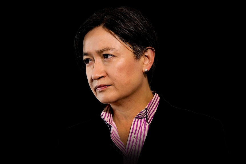 Penny Wong holds a stern expression on her face. She is pictured against a stark, black background