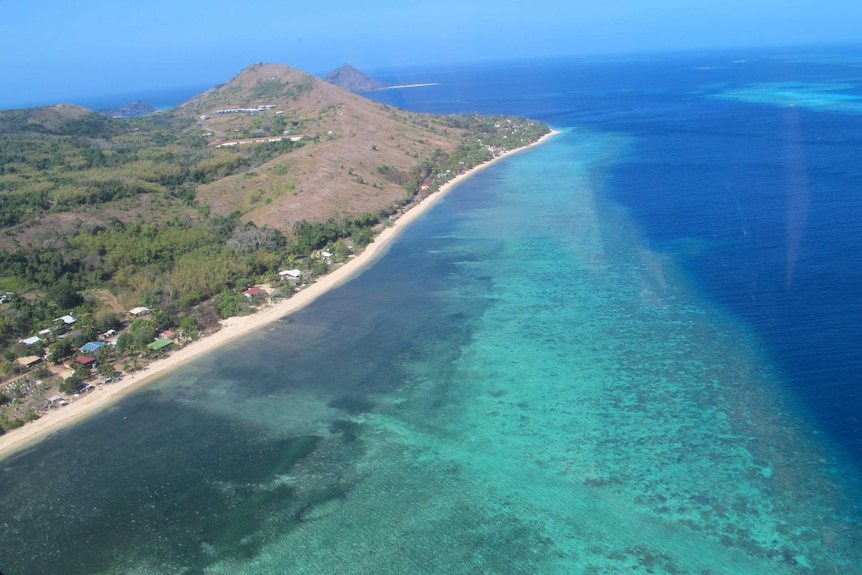 An aerial view of an island in tropical waters.