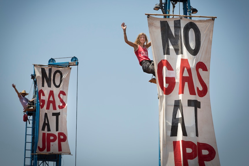 A person climbing up a pole with a sign saying "no gas at JPP"