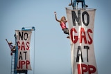 A person climbing up a pole with a sign saying "no gas at JPP"