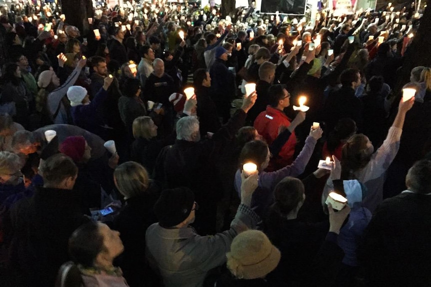 People hold candles up during Canberra Light the Dark vigil