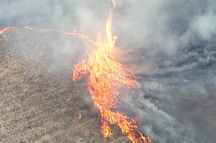 A large flame jumps into the air in aerial footage of a grass fire.