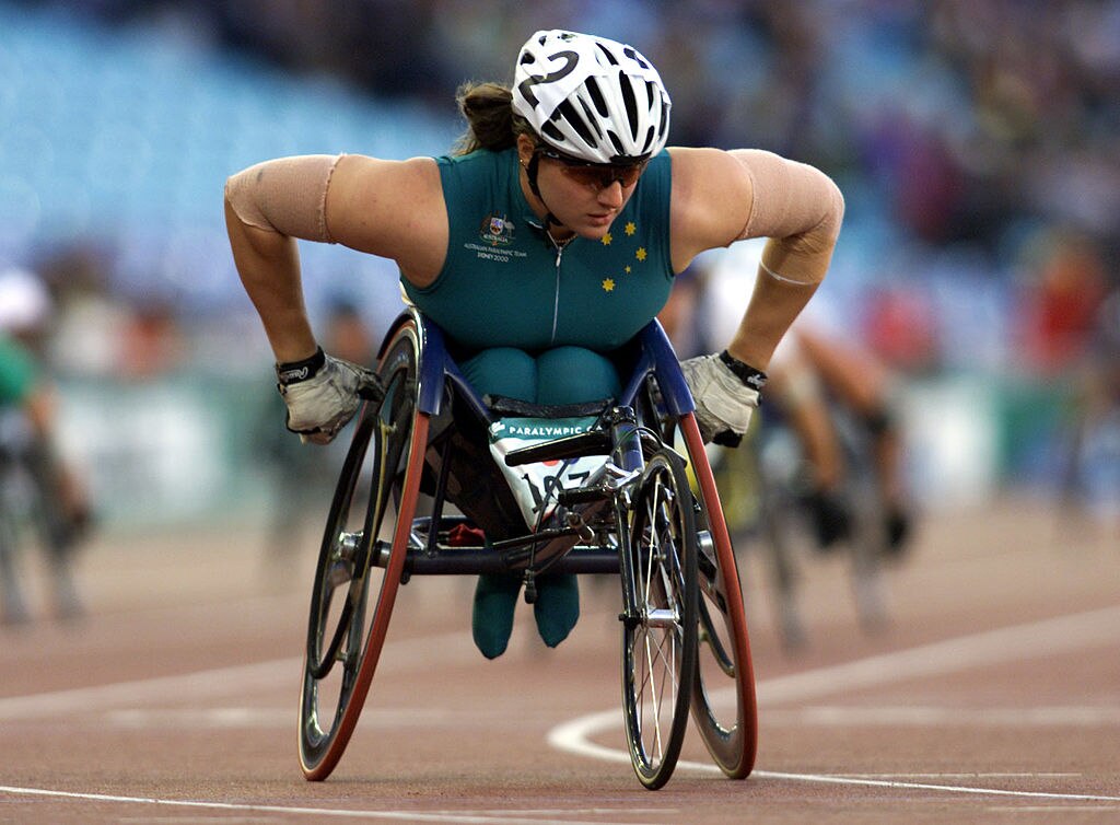 Female athlete uses hands to propel wheelchair in race on track