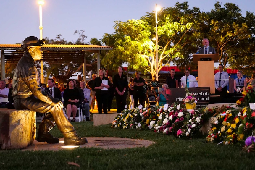 Man speaks at lectern next to new miner memorial statue.