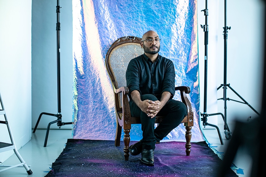 Fashion designer Lokesh Kashyap sitting with purple backdrop, at a shoot.