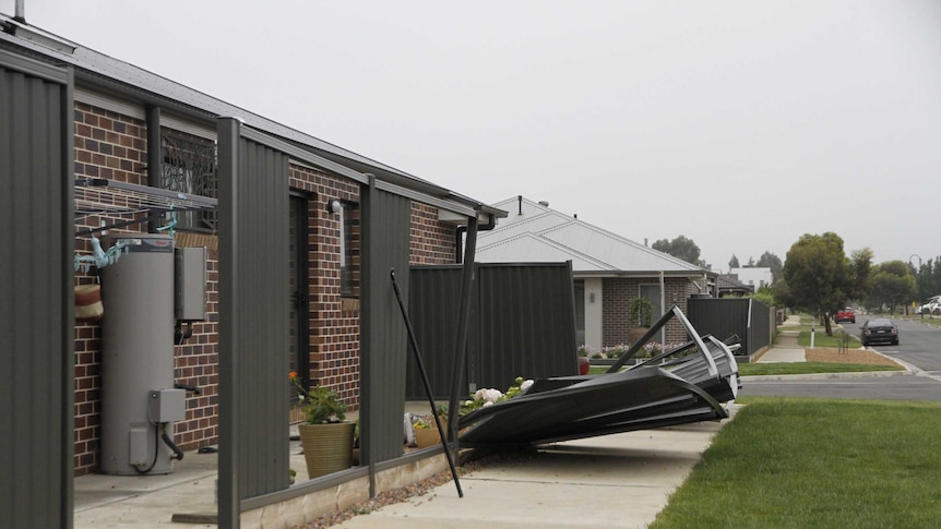 A fence damaged by wind on a footpath.