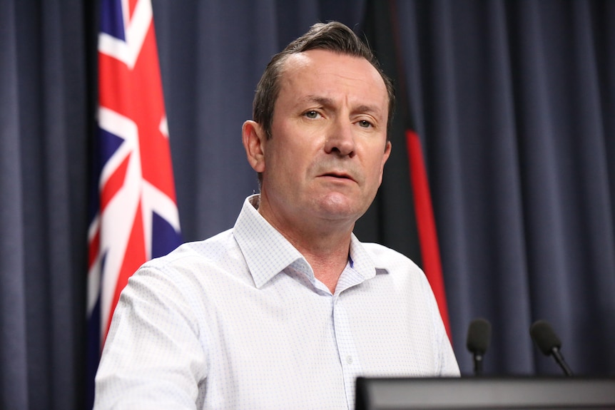 A head and shoulders shot of WA Premier Mark McGowan in a white shirt at a media conference indoors.