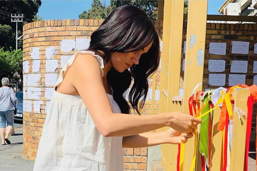 Duchess of Sussex wears casual clothes as she ties a ribbon outside a post office