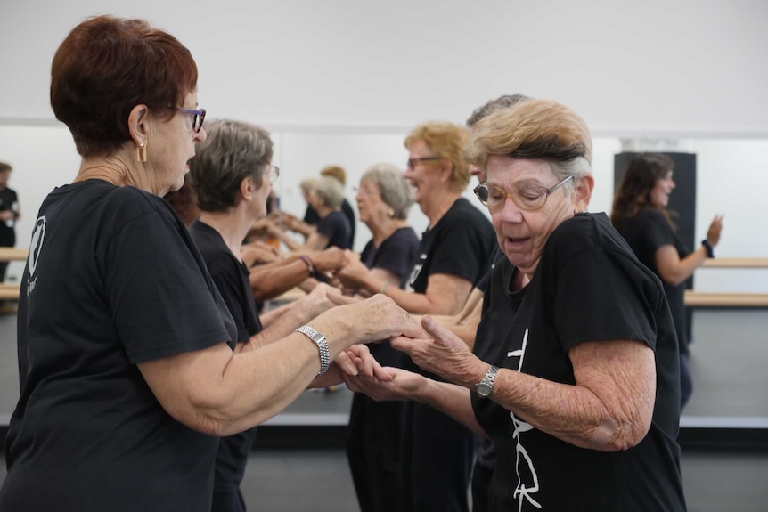 Older women holding hands and dancing at Darwin's Tracks Dance Studio.