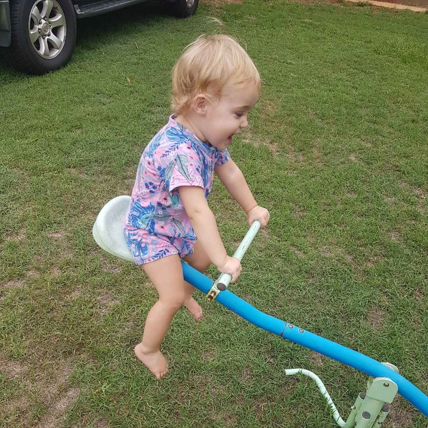 Young toddler laughing on a plastic seesaw.