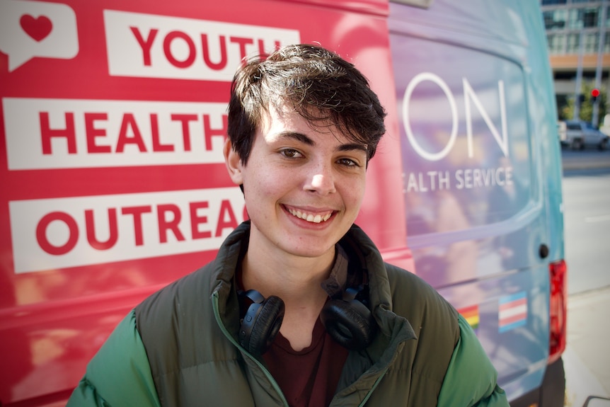 A Canberra teenager smiles in front of a van.
