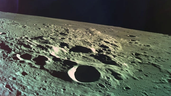 The craters on the surface on the moon can be seen in the foreground while the darkness of space looms in the background.