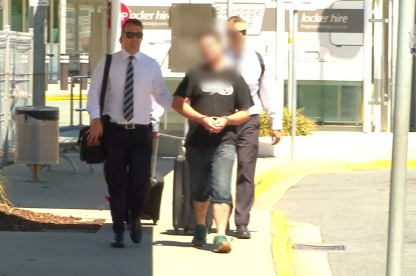 33-year-old man being led by police with handcuffs on, face blurred.