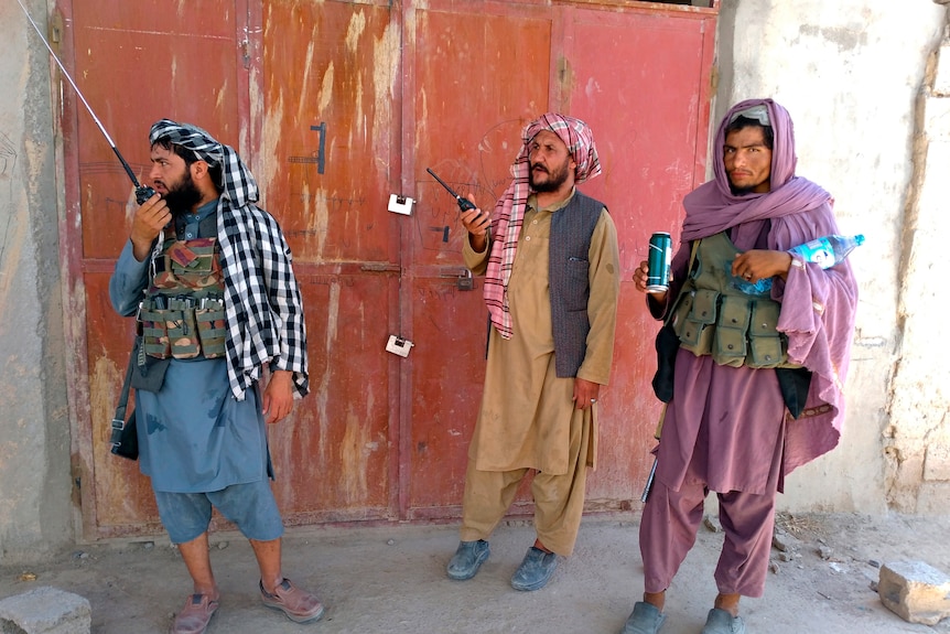 Taliban fighters stand guard at a checkpoint inside the city of Farah