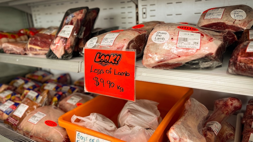 Meat for sale at a butcher's shop with a sign promoting legs of lamb