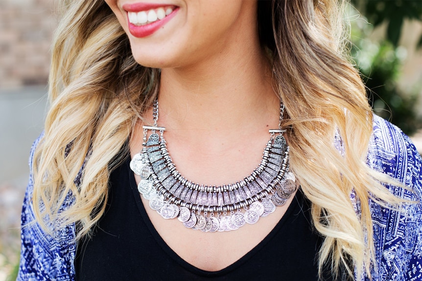 A woman wearing a chunky necklace smiles.