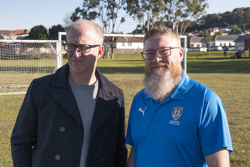 Two men (Clayton Harrison and Steve Manning) standing side by side at a sporting field.
