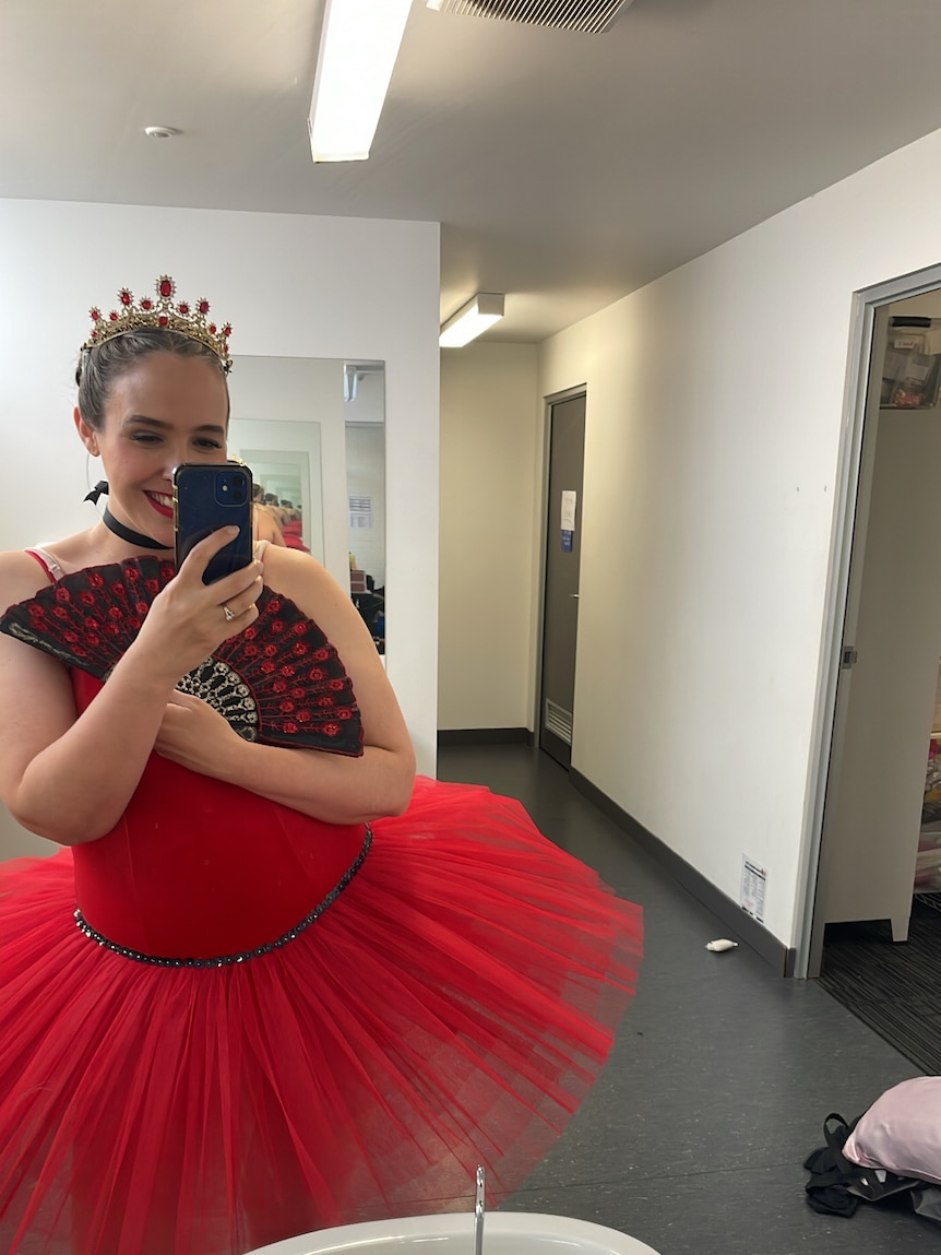 Bec Brewin takes a selfie in a change room while wearing a red tutu and tiara for an upcoming ballet performance.