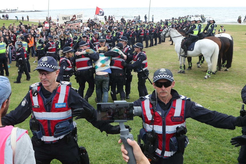 Police keep protesters apart as a man is arrested on the St Kilda foreshore in Melbourne