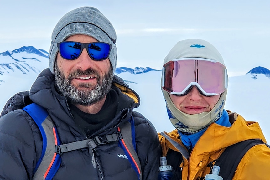 A man and woman side-by-side in heavy winter gear in Antarctica