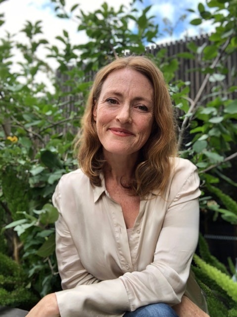 Gillian Singleton outdoors with plants behind her.