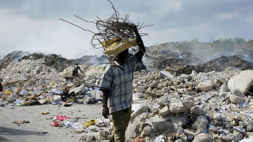 A man carries a bundle of metal bars salvaged from the rubble of collapsed buildings in Port-au-Prin