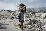 A man carries a bundle of metal bars salvaged from the rubble of collapsed buildings in Port-au-Prin