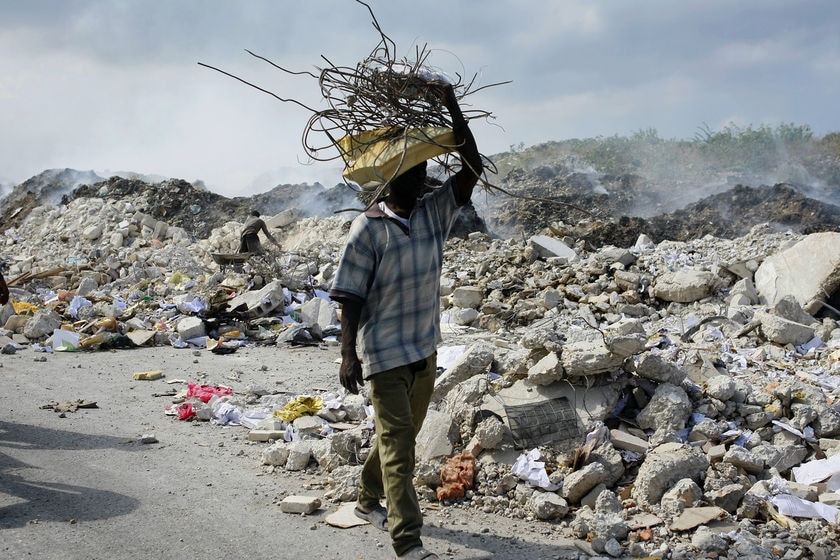 A man carries a bundle of metal bars salvaged from the rubble of collapsed buildings in Port-au-Prin