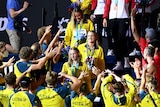 An Australian women's medley relay team walks around the pool after receiving medals at the world titles as teammates cheer. 