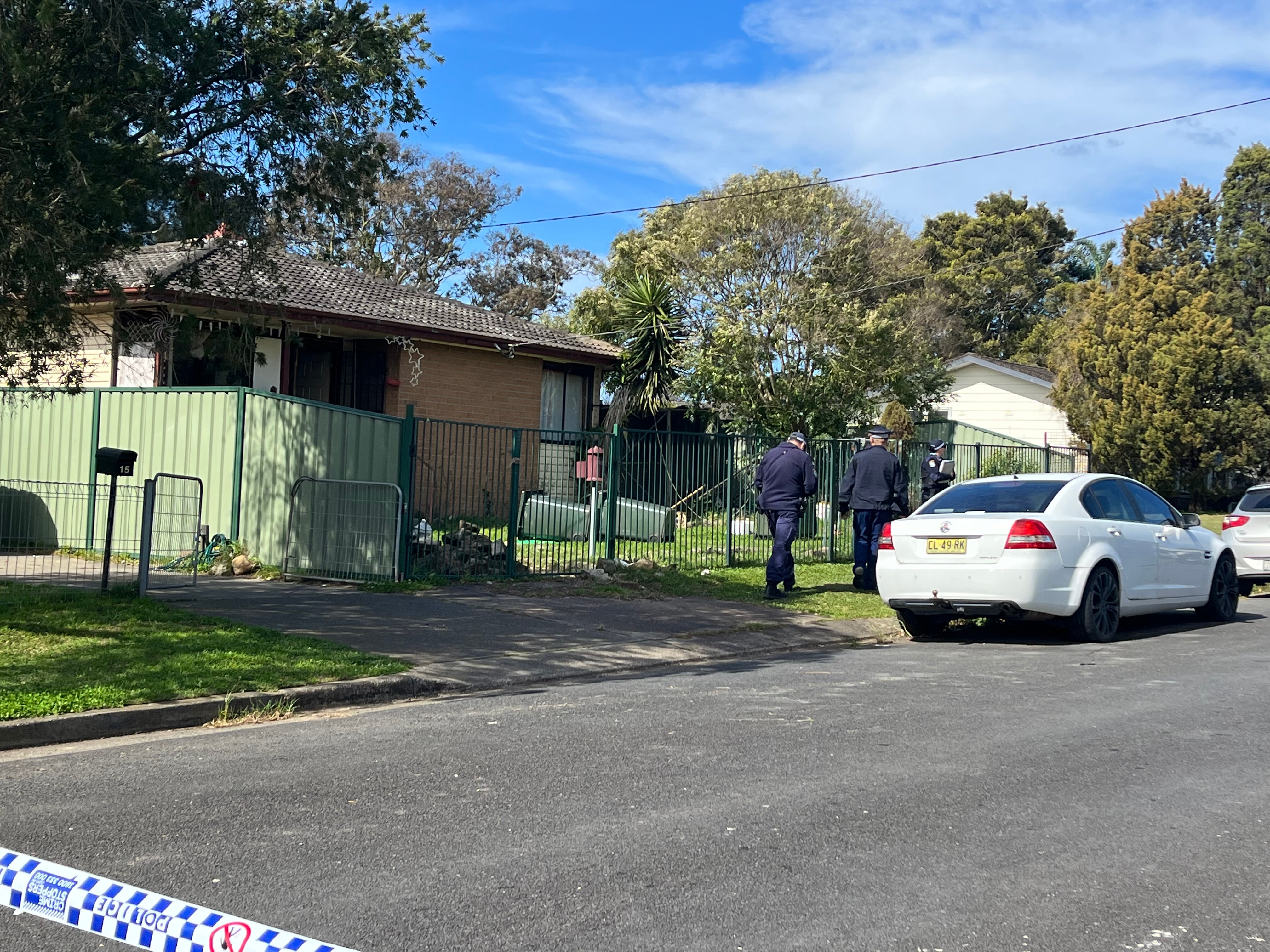 Police officers walking past a house on a suburban street
