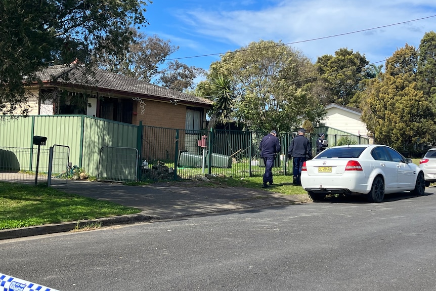 Police officers walking past a house on a suburban street