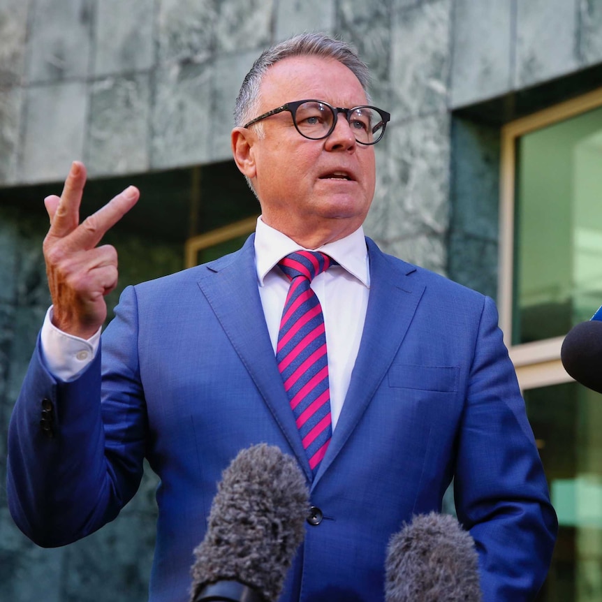 Joel Fitzgibbon holds three fingers up while speaking to the media in a courtyard at parliament house