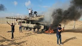 Palestinians celebrate beside a burning tank