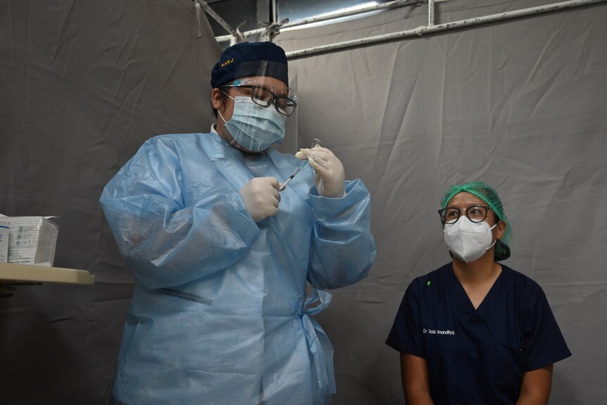 A doctor (right) prepares to receive a vaccine for COVID-19 at a Jakarta hospital
