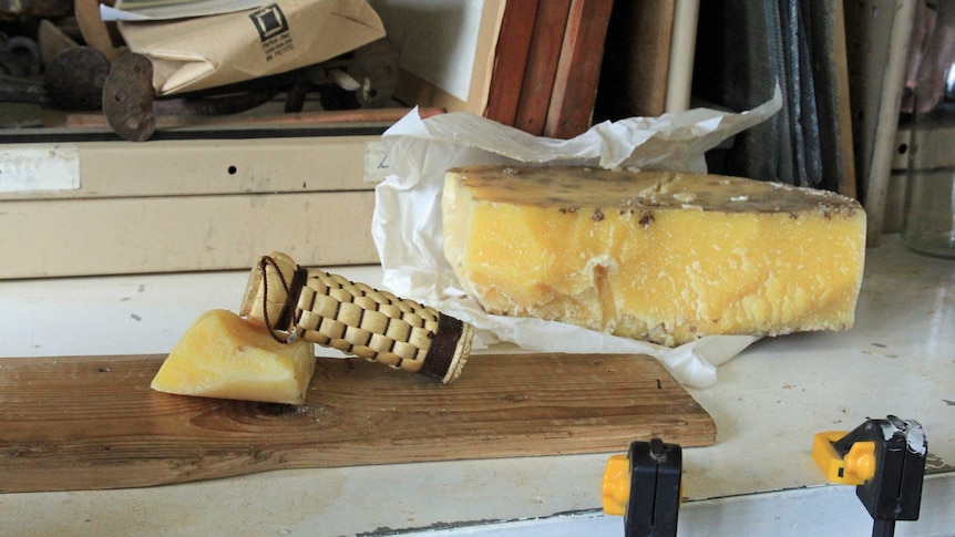 A polissoir on a piece of a timber with a large block of beeswax behind it