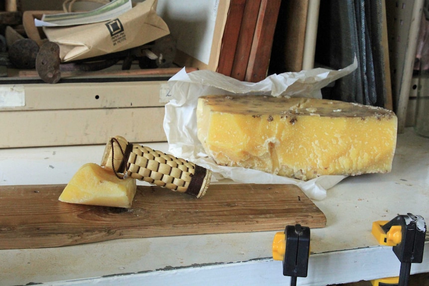 A polissoir on a piece of a timber with a large block of beeswax behind it