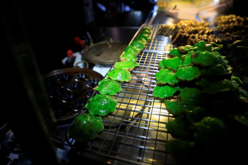 Bright green cakes sit on a cooling rack in a itche. 