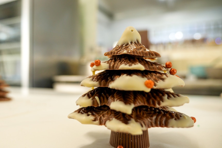 A chocolate Christmas tree is covered in white chocolate and sprinkles. 