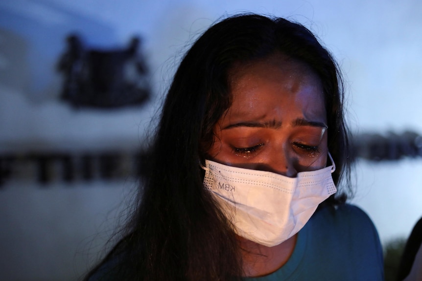 A woman wearing a face mask cries