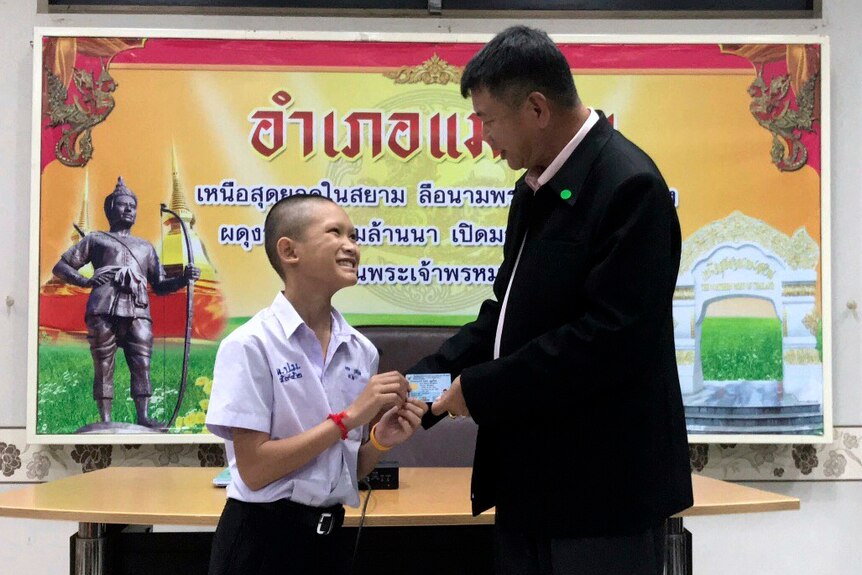 Mongkol Boonpiam, on of the Thai cave boys, smiles as he is handed an identity card.