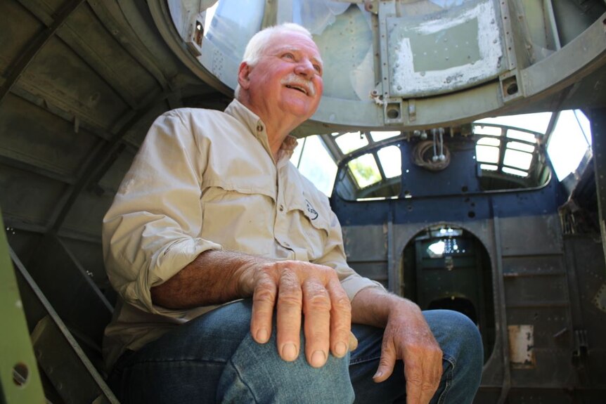 A man sits inside an old plane shell.