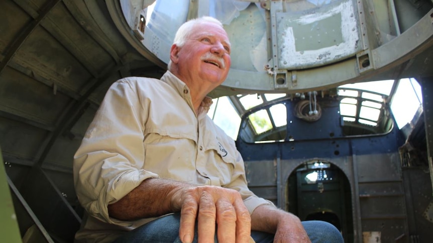 A man sits inside an old plane shell.