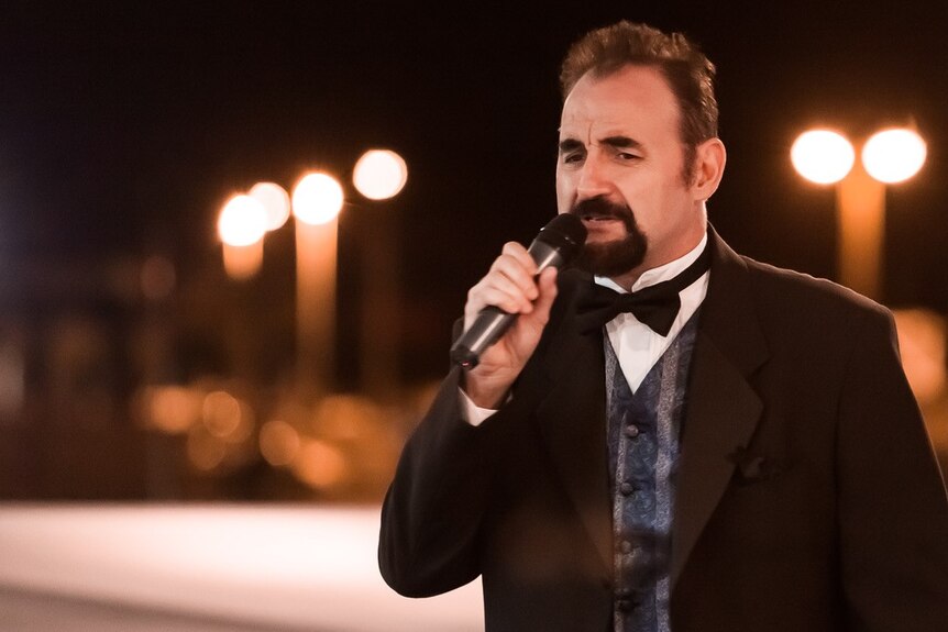 Roger Davy singing at a black tie event.