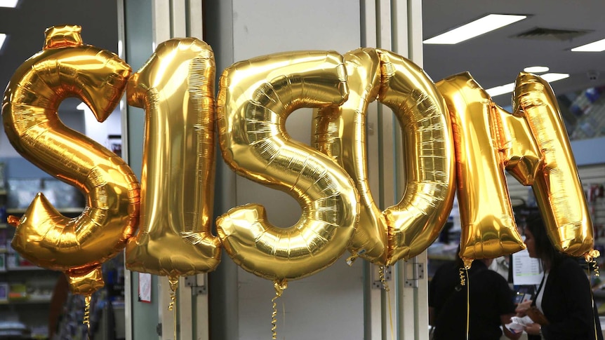 A gold inflatable $150m sign in front of a lotto newsagent.