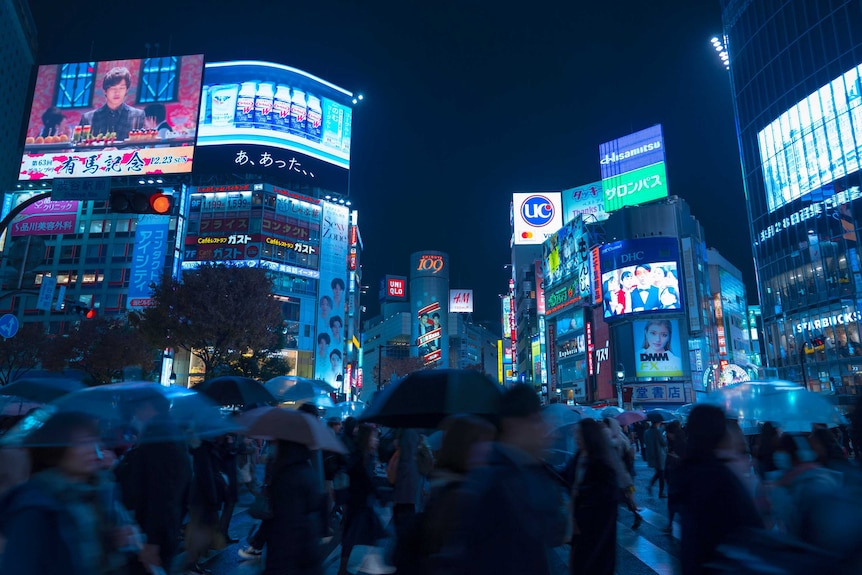 Many people cross the Shibuya street crossing at night