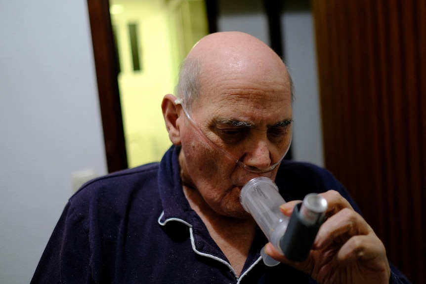 Un hombre con un medicamento para el asma en la boca. 