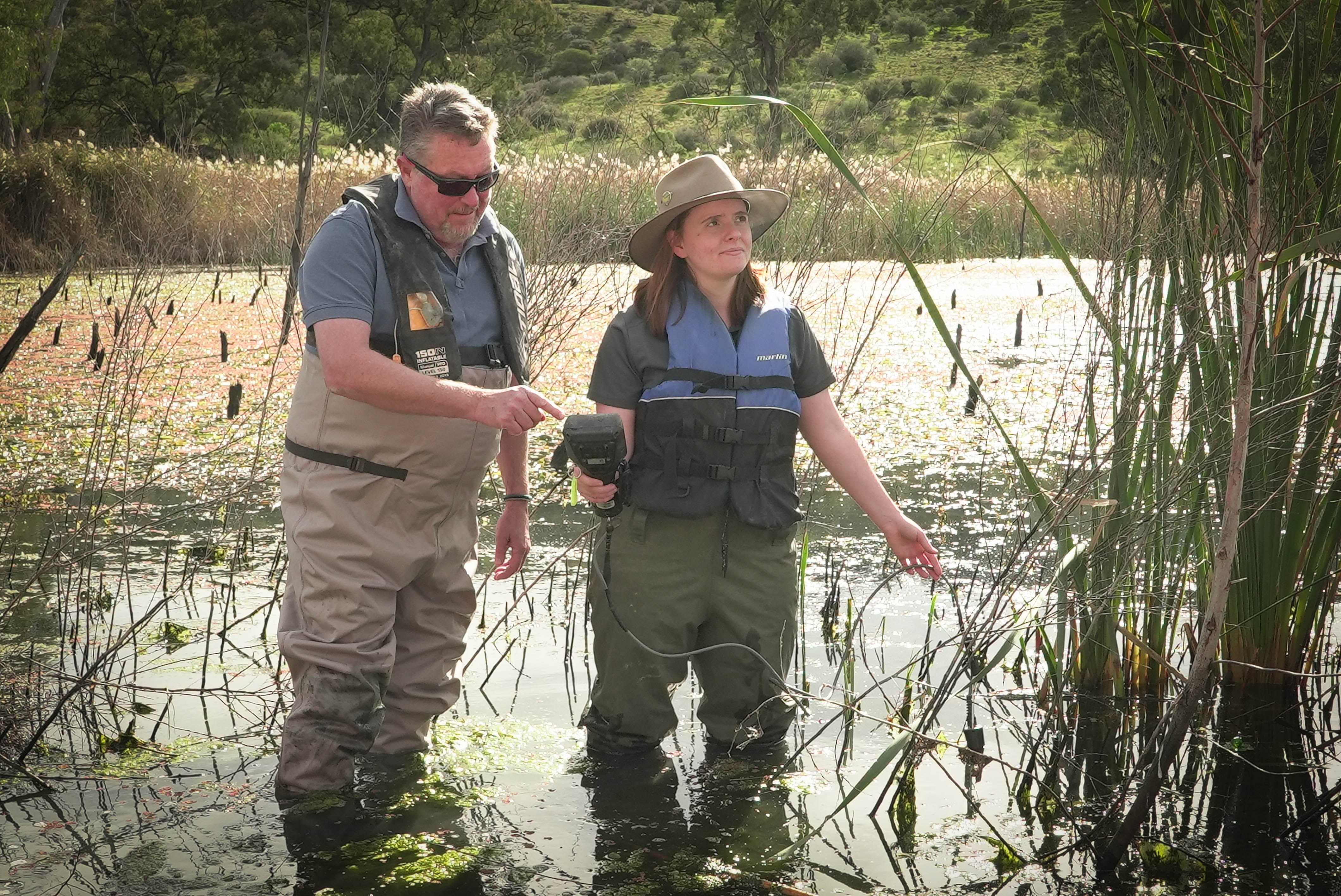A man and woman in waders in a wetland
